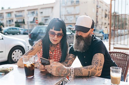 Mature hipster couple looking at smartphone at sidewalk cafe, Valencia, Spain Foto de stock - Sin royalties Premium, Código: 649-09123450