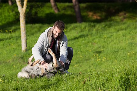 simsearch:649-08840788,k - Man playing with dog in park grass Foto de stock - Sin royalties Premium, Código: 649-09123625