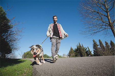 simsearch:649-08840788,k - Mid adult man walking dog in park, low angle view Foto de stock - Sin royalties Premium, Código: 649-09123628