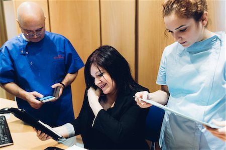 Dentist and dental nurse with patient, looking at digital tablet Stock Photo - Premium Royalty-Free, Code: 649-09138920