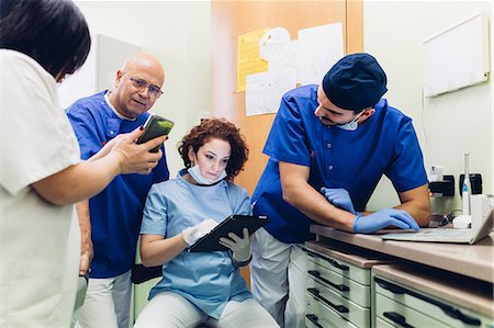 Dentists in dentist office looking at digital tablet, laptop and smartphone Stock Photo - Premium Royalty-Free, Code: 649-09138932