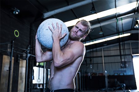 simsearch:649-09139139,k - Man exercising in gymnasium, using atlas stone Stock Photo - Premium Royalty-Free, Code: 649-09139154