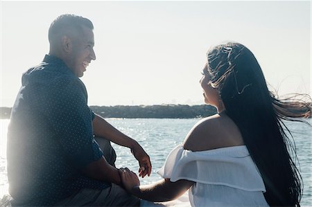 sitting near beach - Couple sitting on coastal rocks, holding hands, smiling Stock Photo - Premium Royalty-Free, Code: 649-09139192