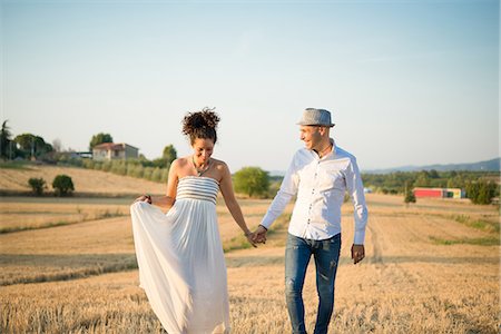 simsearch:649-08901850,k - Heterosexual couple walking through field, holding hands, smiling Photographie de stock - Premium Libres de Droits, Code: 649-09139207