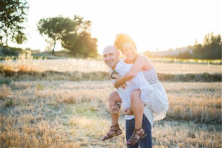 simsearch:649-08901850,k - Portrait of heterosexual couple in field, man carrying woman on back Photographie de stock - Premium Libres de Droits, Code: 649-09139202