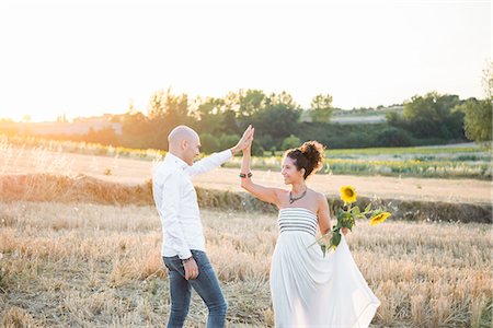 simsearch:649-08901850,k - Heterosexual couple dancing in fields, woman holding sunflowers in hand Photographie de stock - Premium Libres de Droits, Code: 649-09139212