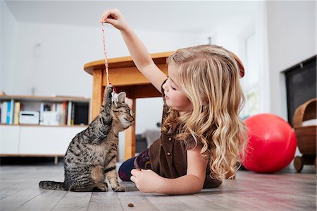 string (not clothing, packaging or instruments) - Young girl lying on floor, playing with pet cat Foto de stock - Sin royalties Premium, Código: 649-09139240