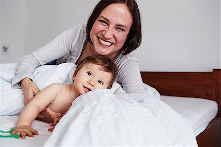 simsearch:649-09139262,k - Mother and baby daughter relaxing on bed, smiling Stock Photo - Premium Royalty-Free, Code: 649-09139258