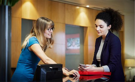 simsearch:649-08714633,k - Two businesswomen looking at smartphone in office reception Photographie de stock - Premium Libres de Droits, Code: 649-09139312