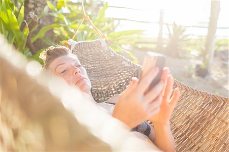 Woman relaxing on hammock, using smartphone,  Nacpan Beach, Palawan, Philippines Stock Photo - Premium Royalty-Free, Code: 649-09148432