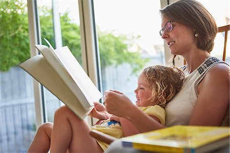 Mother and toddler daughter reading by patio door Stock Photo - Premium Royalty-Free, Code: 649-09148585