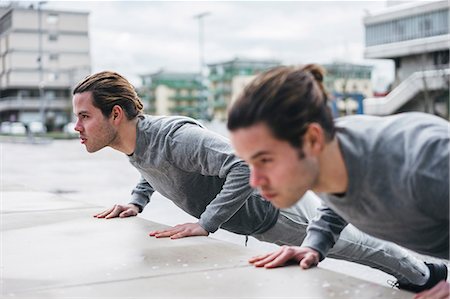 rivalidade entre irmãos - Young male twins doing push ups against wall in city Foto de stock - Royalty Free Premium, Número: 649-09148630