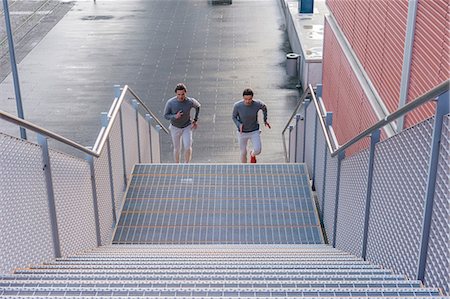 simsearch:649-08238188,k - Young adult male twins running together, running up city stairway Foto de stock - Sin royalties Premium, Código: 649-09148654