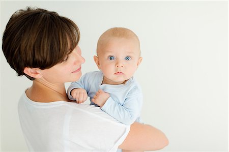 simsearch:649-08119446,k - Mother holding baby boy, looking over shoulder at camera Foto de stock - Sin royalties Premium, Código: 649-09149021