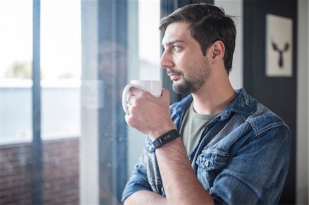simsearch:614-06311914,k - Young man drinking coffee while looking out of  office window Stock Photo - Premium Royalty-Free, Code: 649-09149103