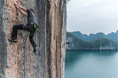 scared asian man - Man rock climbing on limestone rock, Ha Long Bay, Vietnam Foto de stock - Sin royalties Premium, Código: 649-09149110