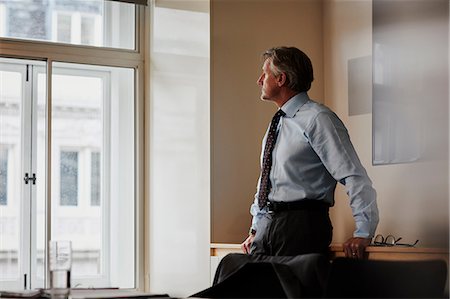 simsearch:614-07487219,k - Businessman in office looking out of window pensively Fotografie stock - Premium Royalty-Free, Codice: 649-09149297