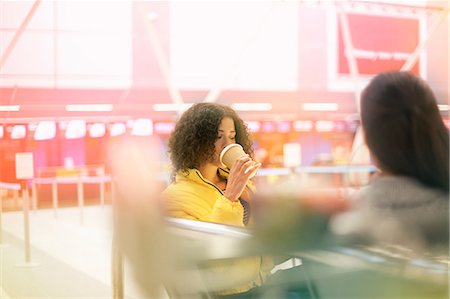 simsearch:649-09213680,k - Two mid adult women drinking takeaway coffee in airport departure lounge Stock Photo - Premium Royalty-Free, Code: 649-09156206