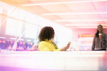 Two mid adult women meeting in airport departure lounge Stock Photo - Premium Royalty-Free, Code: 649-09156207