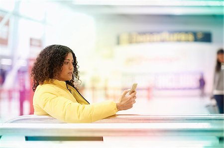 Mid adult woman looking at smartphone in airport departure lounge Stock Photo - Premium Royalty-Free, Code: 649-09156209