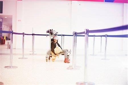 stanchion cordon - Portrait of girl sitting on luggage trolley in airport departure lounge Stock Photo - Premium Royalty-Free, Code: 649-09156212