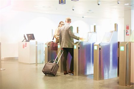 Businessman and woman walking through security gate at airport, low angle view Fotografie stock - Premium Royalty-Free, Codice: 649-09156287