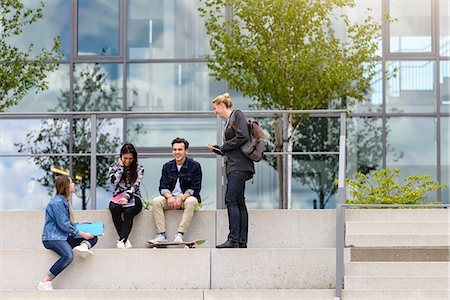 simsearch:649-09206130,k - Four young adult students sitting chatting on stairway outside college Photographie de stock - Premium Libres de Droits, Code: 649-09159186