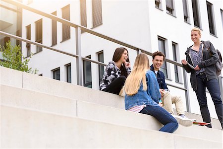 simsearch:649-09206130,k - Four young adult students sitting chatting on stairway outside college, low angle view Photographie de stock - Premium Libres de Droits, Code: 649-09159189