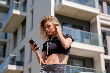simsearch:614-07652557,k - Young woman listening to music on mobile phone, building in background Stock Photo - Premium Royalty-Free, Code: 649-09159254