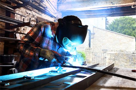 Blacksmith welding metal on workbench in blacksmiths shop Foto de stock - Sin royalties Premium, Código: 649-09159361