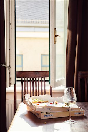 Leftover pizza in box and wine glass on dining table Stock Photo - Premium Royalty-Free, Code: 649-09159500