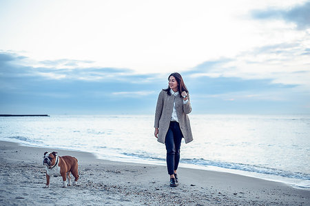 pet with owner - Young woman walking along beach with pet dog Stock Photo - Premium Royalty-Free, Code: 649-09176614