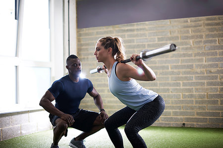 Trainer watching female client do squats with barbell in gym Stock Photo - Premium Royalty-Free, Code: 649-09176901