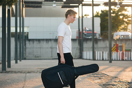 Young musician carrying guitar in case Foto de stock - Sin royalties Premium, Código: 649-09176935