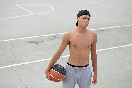 simsearch:649-09182176,k - Male teenage basketball player with ball on basketball court, portrait Fotografie stock - Premium Royalty-Free, Codice: 649-09182179