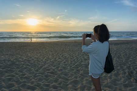 simsearch:649-09148811,k - Woman taking photograph of sunset on beach Stock Photo - Premium Royalty-Free, Code: 649-09182339