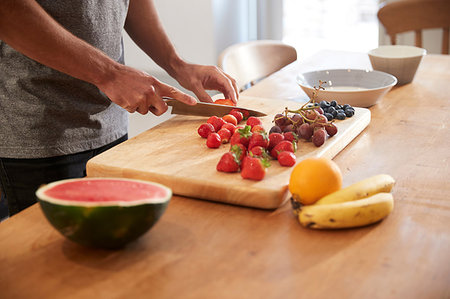 simsearch:649-09268999,k - Young man slicing fresh fruit at kitchen table, mid section Photographie de stock - Premium Libres de Droits, Code: 649-09182379