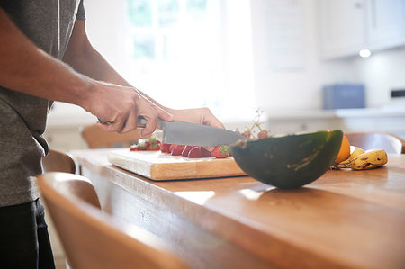 simsearch:649-09268999,k - Young man slicing fresh fruit at kitchen table, mid section Photographie de stock - Premium Libres de Droits, Code: 649-09182382