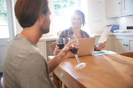 Couple at kitchen table drinking red wine while doing paperwork Stock Photo - Premium Royalty-Free, Code: 649-09182397