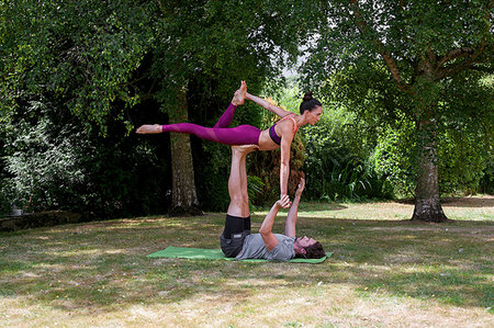 simsearch:400-06872008,k - Young man practicing yoga in garden, lying on back balancing woman on feet Fotografie stock - Premium Royalty-Free, Codice: 649-09195582