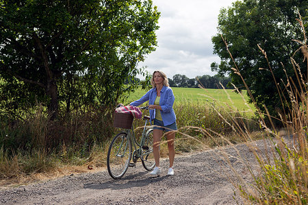 simsearch:649-08232809,k - Mature woman pushing bicycle along rural road Stock Photo - Premium Royalty-Free, Code: 649-09195596