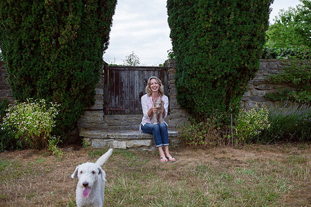 simsearch:649-08714973,k - Mature woman with two dogs sitting in garden, portrait Foto de stock - Sin royalties Premium, Código: 649-09195611