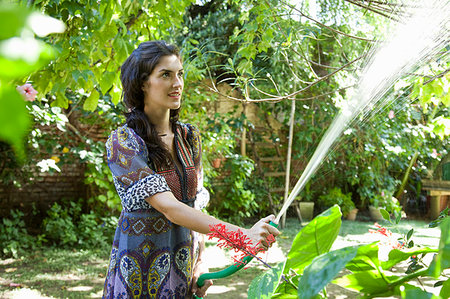 stand up squirting - Woman watering plants in tropical garden Stock Photo - Premium Royalty-Free, Code: 649-09205688