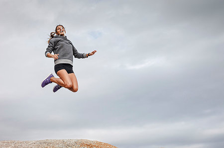 simsearch:649-02290457,k - Woman jumping for joy on boulder Photographie de stock - Premium Libres de Droits, Code: 649-09206413