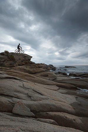 Man sitting on bicycle on boulder Stock Photo - Premium Royalty-Free, Code: 649-09206423