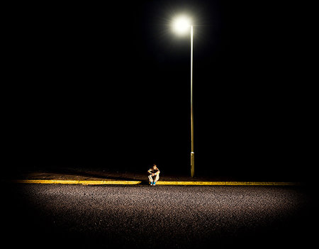 simsearch:649-07560496,k - Boy sitting on pavement at night with street lights Foto de stock - Sin royalties Premium, Código: 649-09206853