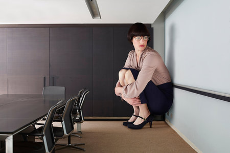 simsearch:614-08875291,k - Businesswoman crouching in small conference room Photographie de stock - Premium Libres de Droits, Code: 649-09207098