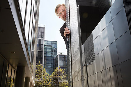 simsearch:614-08875291,k - Oversized businessman peering from behind skyscrapers, low angle view Photographie de stock - Premium Libres de Droits, Code: 649-09207100