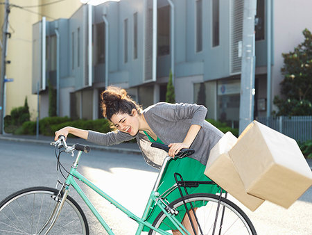 fallen cardboard boxes - Young woman with bicycle and falling cardboard boxes Stock Photo - Premium Royalty-Free, Code: 649-09207695