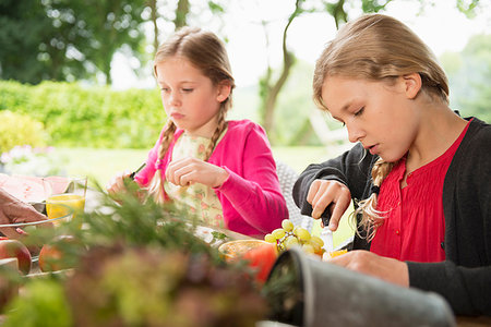 simsearch:649-08950750,k - Two sisters at patio table slicing fresh fruit Stock Photo - Premium Royalty-Free, Code: 649-09207862